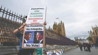 A protester holds sign bearing pro-Palestinian slogans and urging people to not vote for the Conservative and Labour parties, outside the Houses of Parliament in Westminster. Image: Reuters
