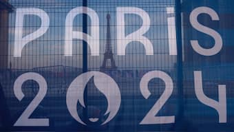 The Eiffel Tower is seen behind a Paris Olympics canvas. AP
