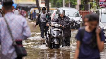 A commuter makes his way through a waterlogged road after rains, in Mumbai, July 25, 2024. PTI