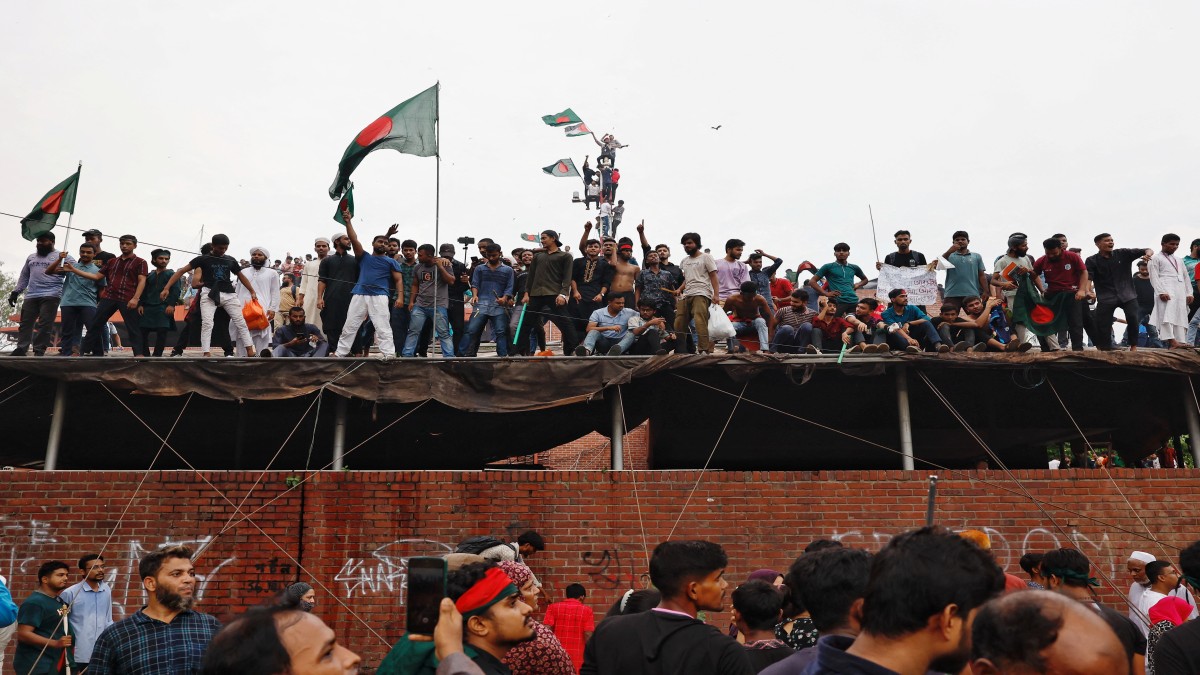 People waves Bangladeshi flags on top of the Ganabhaban, the Prime Minister's residence, as they celebrate the resignation of PM Sheikh Hasina in Dhaka, Bangladesh, August 5, 2024. Reuters People waves Bangladeshi flags on top of the Ganabhaban, the Prime Minister's residence, as they celebrate the resignation of PM Sheikh Hasina in Dhaka, Bangladesh, August 5, 2024. Reuters