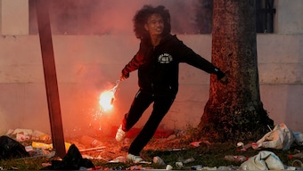 A demonstrator throws a flare as they clash with riot police during a protest against planned controversial revisions to election law outside the Indonesian Parliament building in Jakarta. Reuters