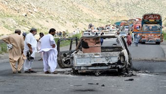 People look at a charred vehicle near a collapsed railway bridge the morning after a blast by separatist militants at Kolpur in Bolan district, Balochistan province. AFP