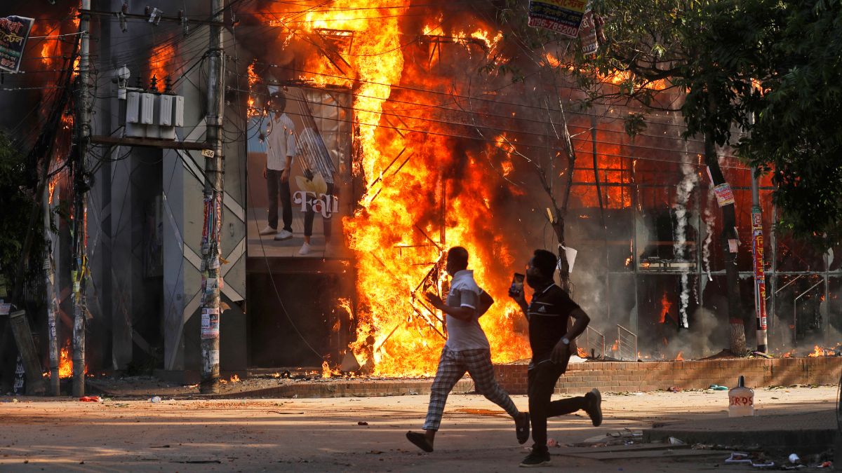 People run past a shopping center which was set on fire in Dhaka, Bangladesh. (Photo: AP) People run past a shopping center which was set on fire in Dhaka, Bangladesh. (Photo: AP)