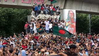 Protesters climb a public monument as they celebrate the news of Prime Minister Sheikh Hasina's resignation, in Dhaka, Bangladesh. AP
