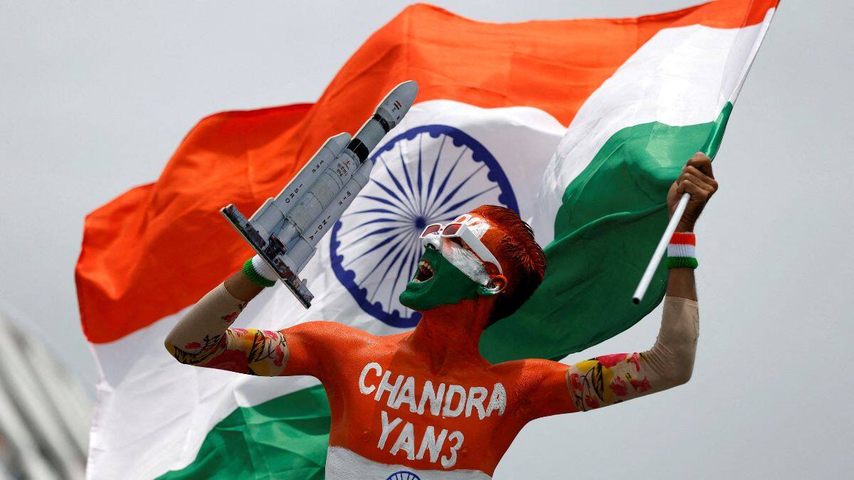 An enthusiast with his body painted in tri-colours reacts as he holds up a model of LVM3 M4 which was used in launching of Chandrayaan-3 spacecraft on the eve of its moon landing, in Ahmedabad, India, August 22, 2023. File Image/Reuters