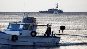 A fishing boat sails past a finance police vessel and a coast guard vessel operating in the sea to search for the missing, including British entrepreneur Mike Lynch, after a luxury yacht sank off the coast of Porticello, near the Sicilian city of Palermo, Italy, on Tuesday. Reuters