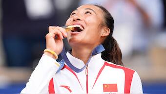 Zheng Qinwen bites her gold medal after winning the women's singles tennis final at the 2024 Paris Olympics. AP
