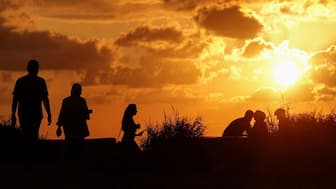People walk and sit by the sea while the sun sets over Beirut, Lebanon. The company Reflect Orbital has proposed to reflect the rays of the Sun over solar panels on the surface of the Earth when it is dark after sunset. Representational image/Reuters


