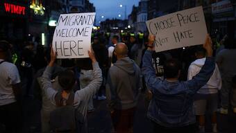 People hold anti-racism placards during a counter demonstration against an anti-immigration protest called by far-right activists, near an Immigration Solicitors' office in Westcliff, near Southend-on-Sea, eastern England. AFP