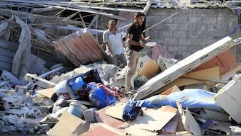 Men stand on the rubble of a building hit in an Israeli airstrike in the southern village of Akbieh, Lebanon. AP