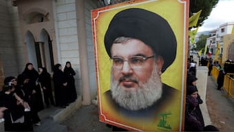 People stand near a picture of Hezbollah leader Sayyed Hassan Nasrallah during the funeral of Hezbollah member Ali Mohamed Chalbi, in Kfar Melki, Lebanon, September 19, 2024. File Image/Reuters