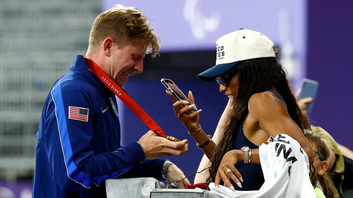 Para-sprinter Hunter Woodhall gets his gold medal photographed by wife Tara Davis-Woodhall, who had won gold in the women's long jump event in the Olympics last month. Reuters Para-sprinter Hunter Woodhall gets his gold medal photographed by wife Tara Davis-Woodhall, who had won gold in the women's long jump event in the Olympics last month. Reuters