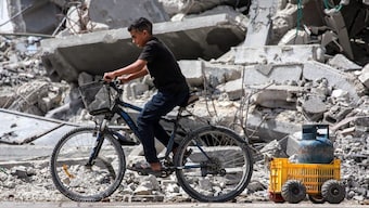 A boy rides a cycle pulling a cart loaded with a cooking gas canister past the rubble of a collapsed building in Khan Yunis in the southern Gaza Strip on September 16, 2024 amid the ongoing war in the Palestinian territory between Israel and Hamas. Source: AFP.