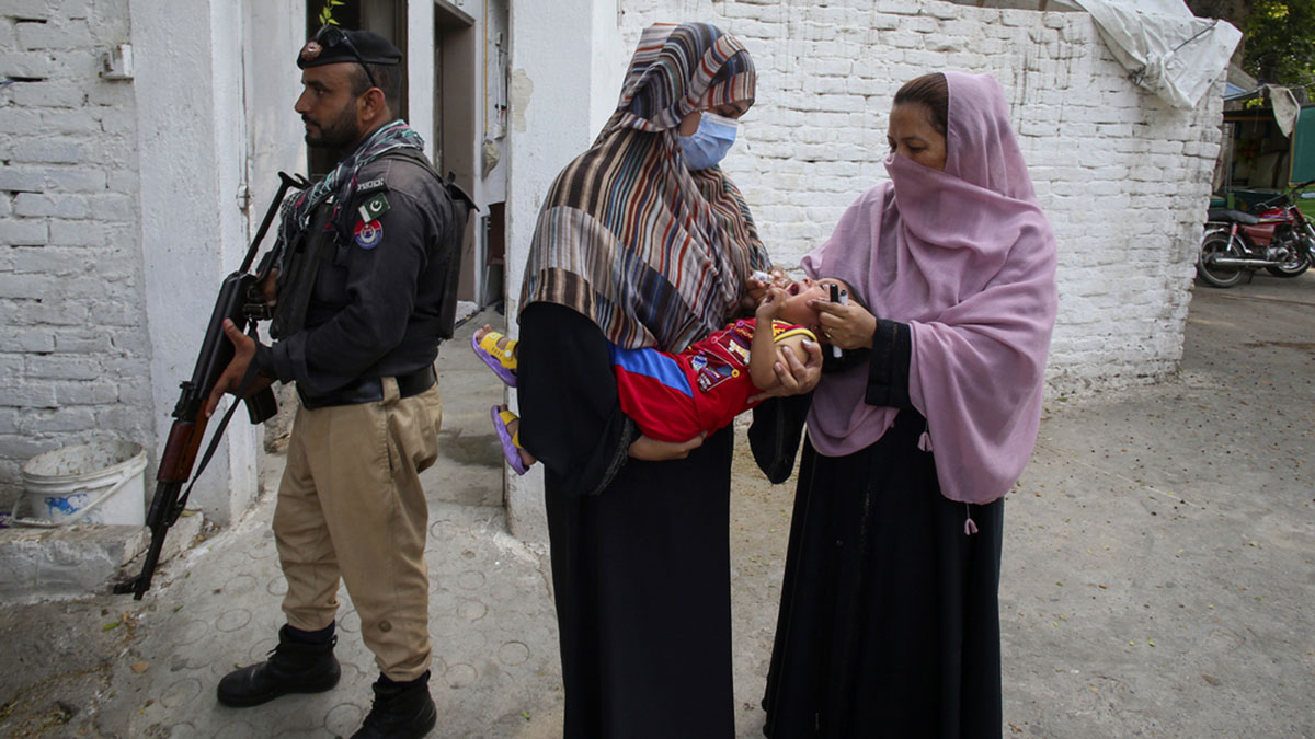 A police officer stands guard as a health worker, right, administers a polio vaccine to a child in a neighbourhood of Peshawar, Pakistan on Sept. 9, 2024. AP A police officer stands guard as a health worker, right, administers a polio vaccine to a child in a neighbourhood of Peshawar, Pakistan on Sept. 9, 2024. AP