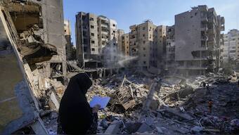 A woman reads the Quran at the site of the assassination of Hezbollah chief Hassan Nasrallah. AP