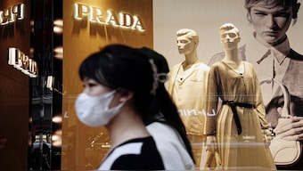 Shoppers walk past a Prada luxury store in China. The economic slowdown has led many in China to opt for dupes rather than high-end luxury brands. Representational image/Reuters