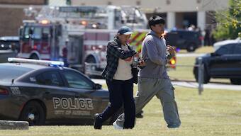 People walk as law enforcement officers work at the scene of a shooting at Apalachee High School in Winder, Georgia. A 14-year-old gunman killed four people in the shooting using an "AR-platform-style weapon". Reuters