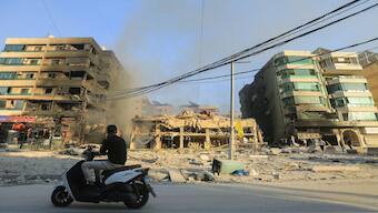 A man rides a motorcycle past destroyed and damaged buildings at the site of an overnight Israeli airstrike that targeted Beirut’s southern suburbs on October 27, 2024. AFP