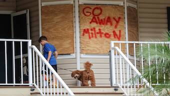 Noah Weibel and his dog Cookie climb the steps to their home as their family prepares for Hurricane Milton on Monday, October 7, 2024, in Port Richey, Florida. AP