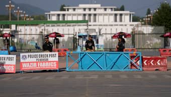 Police officers stand guard at a barricaded road leading to Presidency, in background, and to the venue of the upcoming Shanghai Cooperation Organization (SCO) summit in Islamabad. AP