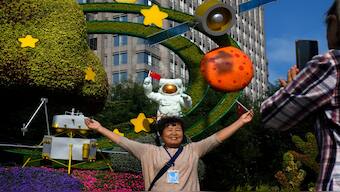 A woman holds a national flag near a floral display featuring a theme of China Space Mission, in Beijing. AP
