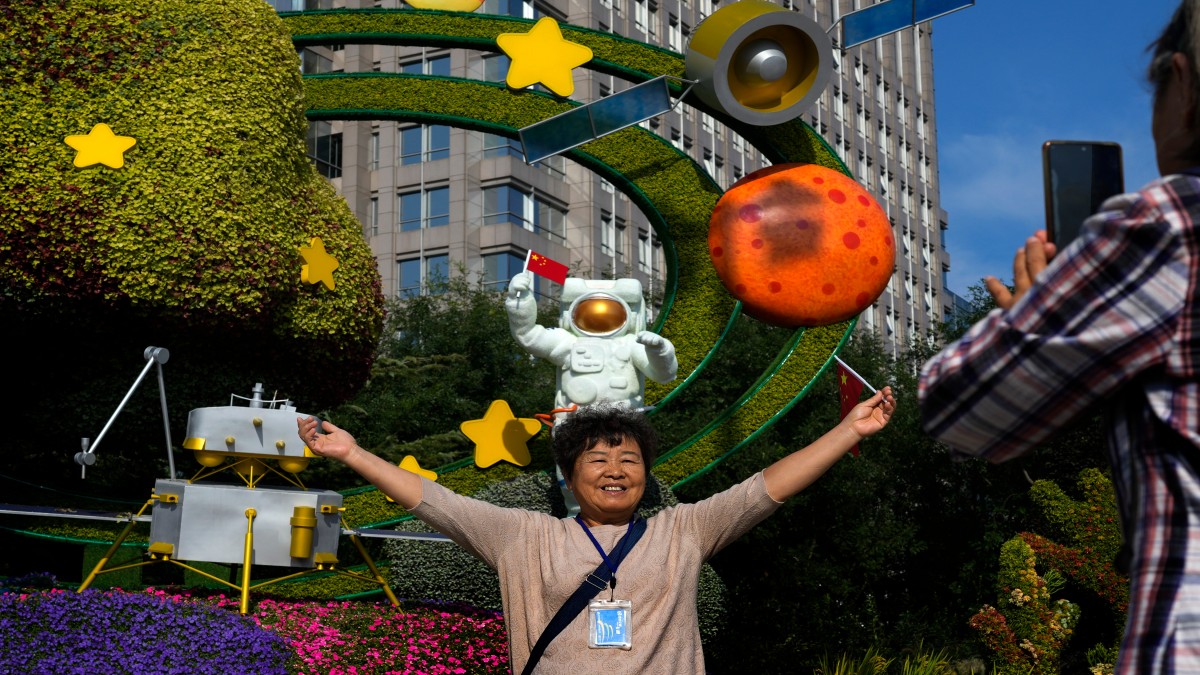 A woman holds a national flag near a floral display featuring a theme of China Space Mission, in Beijing. AP A woman holds a national flag near a floral display featuring a theme of China Space Mission, in Beijing. AP