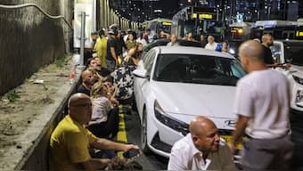 Israelis take cover behind vehicles under a bridge along the side of a highway in Tel Aviv. AFP