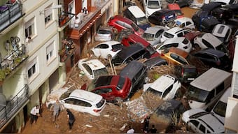 Residents clean the street next to cars piled up after being swept away by floods in Valencia, Spain, Wednesday, Oct. 30, 2024. AP