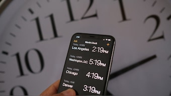 This photo shows a clock in the background of a smartphone showing the time after daylight saving time was implemented in Los Angeles, California, on March 15, 2022. AFP
