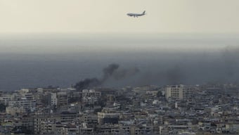 A Middle East Airlines airplane flies over Beirut as smoke from ISraeli airstrikes in Dahiyeh, Beirut. AP