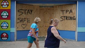 People walk past boarded up storefronts in Tampa ahead of Hurricane Milton's expected landfall in Florida.  Hurricane Milton exploded in strength to become a potentially catastrophic Category 5 storm bound for Florida, threatening the US state with a second ferocious hurricane in as many weeks. AFP