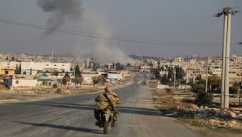 Smoke rises as a member of the rebels led by the Islamist militant group Hayat Tahrir al-Sham drives on a motorbike in al-Rashideen, Aleppo province, Syria November 29, 2024. Reuters