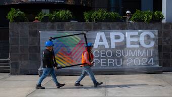 Employees walk in front of a banner at the government complex where the Asia-Pacific Economic Cooperation (APEC) Summit will take place in Lima on November 13, 2024. AFP
