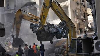 An excavator removes a destroyed car as rescue workers gather at the site of an Israeli airstrike that hit central Beirut, Lebanon. AP