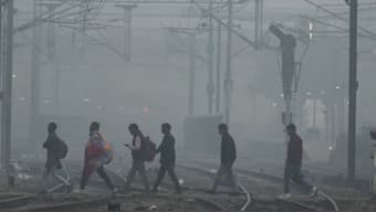 People cross railway tracks on a smoggy morning in New Delhi. Source: REUTERS | FILE.