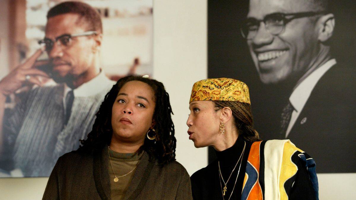 Attallah Shabazz (R) and Malaak Shabazz, two of the six daughters of the late Malcolm X and Betty Shabazz, sit together beneath two portraits of their late father during a news conference at the New York Public Library's Schomburg Center for Research in Black Culture in New York, January 7, 2003. File Image/Reuters
