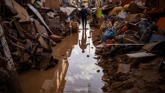 A person walks through a street with piled furniture and rubbish on the sides, in an area affected by floods in Paiporta, Valencia, Spain, Tuesday, Nov. 5, 2024.- AP