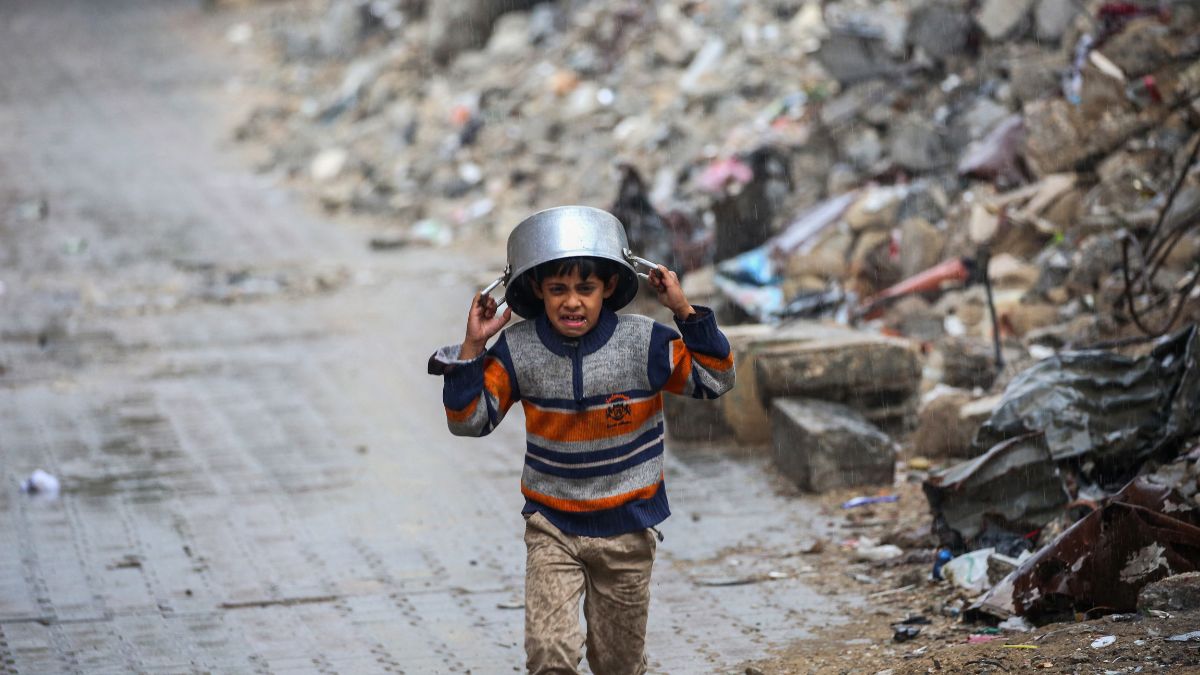 A displaced boy covers his head with a pan as he runs from the rain past building rubble at the Bureij refugee camp in the central Gaza Strip on November 24, 2024, amid the ongoing war between Israel and the Palestinian Hamas militant group. Image- AFP
A displaced boy covers his head with a pan as he runs from the rain past building rubble at the Bureij refugee camp in the central Gaza Strip on November 24, 2024, amid the ongoing war between Israel and the Palestinian Hamas militant group. Image- AFP