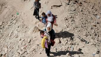 Women carry their children while crossing from Lebanon into Syria on foot at the Masnaa border crossin. Image- Reuters 