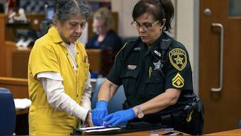 Susan Lorincz, left, who fatally shot a Black neighbour through her front door during an ongoing dispute, is finger printed after she was sentenced to 25 years in prison at a court hearing. AP