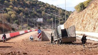 People in Lebanon cross a crater caused by an Israeli strike in the area of Masnaa on the Lebanese side of the border crossing with Syria, on November 20. AFP
