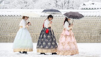 Visitors wearing traditional hanbok dresses are seen on the grounds of Gyeongbokgung Palace amid heavy snowfall in central Seoul on November 27, 2024. AFP