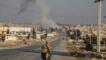 Smoke rises as a member of the rebels led by the Islamist militant group Hayat Tahrir al-Sham drives on a motorbike in al-Rashideen, Aleppo province, Syria November 29, 2024. Reuters