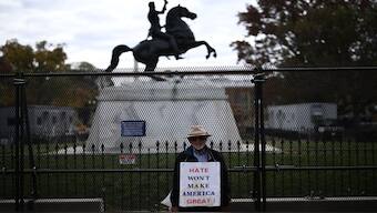 A man holds a sign next to metal fencing installed near the White House in Washington, DC, ahead of election day.  AFP