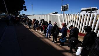 Migrants stand in line to have their papers checked before crossing into the US in Tijuana, Mexico. Reuters