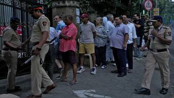 People queue to cast their votes, outside a polling station, as police officers stand guard on the day of the Maharashtra state elections, in Mumbai. Reuters
