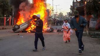 People run past burning vehicles of Bharatiya Janata Party (BJP) MLA during a protest to condemn the alleged killing of women and children in Imphal, in Manipur. AFP