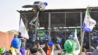 A farmer climbs atop the barricade at Shambhu border after famers commenced their foot march to Delhi, in Patiala district, Punjab. PTI