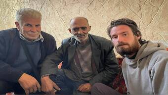 In this photo provided by the Syrian Emergency Task Force, American Travis Timmerman, right, sits with Mosaed al-Rifai, center, who found him in the Syrian desert, and the owner of the house where he took refuge, left, name not available, in Damascus, Syria on Thursday December 12, 2024. AP