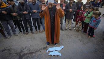 Imam Islam Abu Suaied prays over the bodies of two babies before their burial at the Al-Aqsa Martyrs Hospital in Deir al-Balah, central Gaza Strip. AP